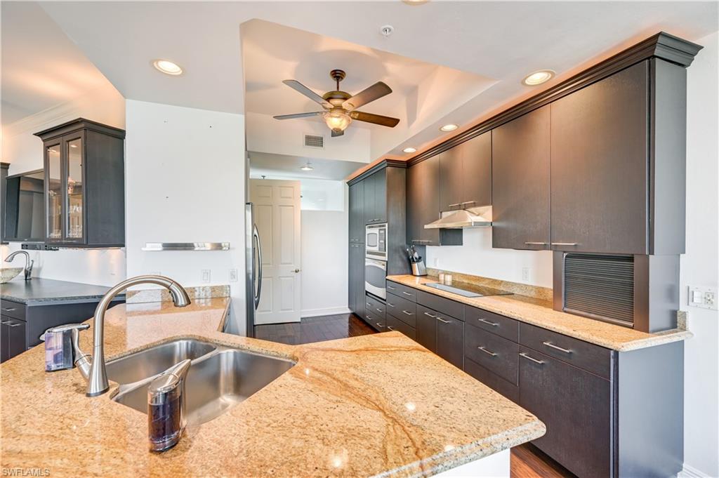 705 10th Street South, Unit 301 Naples, FL 34102 - Photo 5 of 35 a large kitchen with kitchen island a sink stainless steel appliances and cabinets