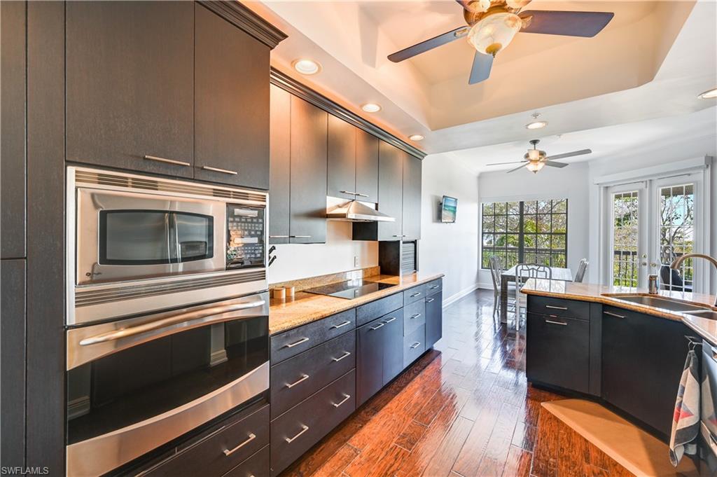705 10th Street South, Unit 301 Naples, FL 34102 - Photo 6 of 35 a kitchen with stainless steel appliances kitchen island granite countertop a stove and a sink