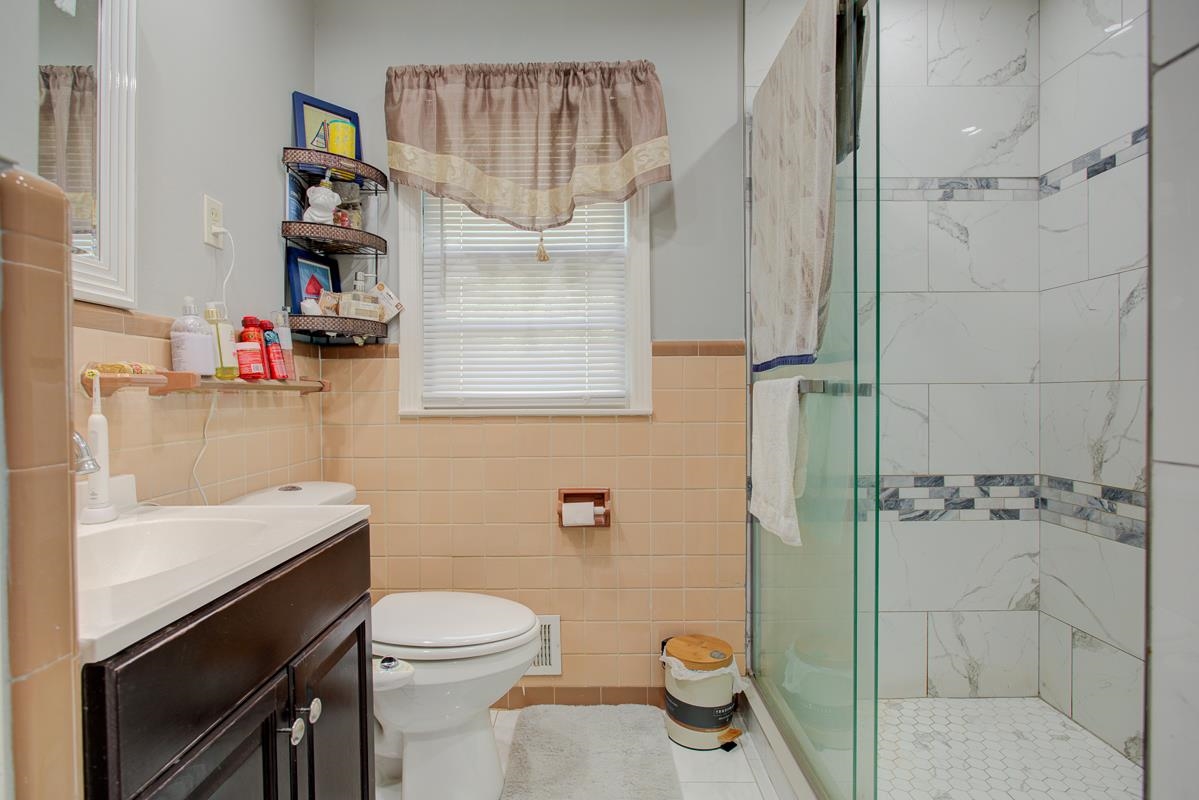 1019 Tatum Road Memphis, TN 38122 - Photo 11 of 21 Bathroom with vanity, tile walls, a shower stall, a wainscoted wall, and tile patterned floors