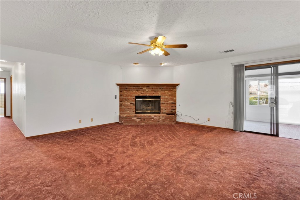 16224 Olalee Road Apple Valley, CA 92307 - Photo 17 of 48 an empty room with a fireplace and fan