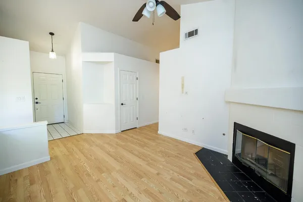 a view of empty room with fireplace and a ceiling fan