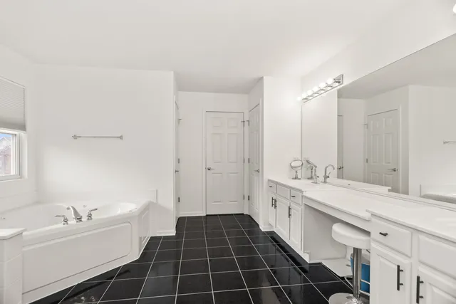 a spacious bathroom with a double vanity sink a mirror and a bathtub