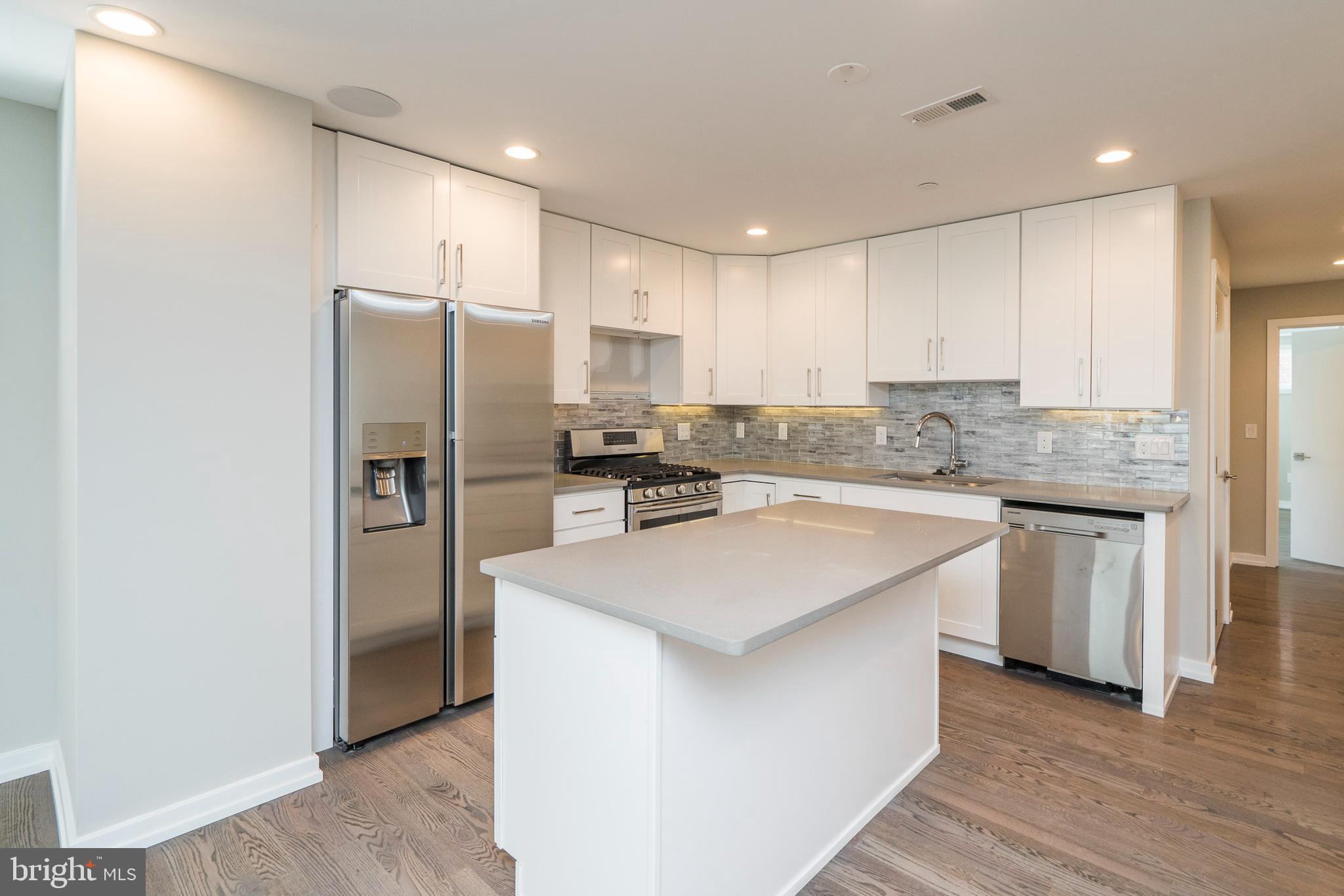 1701 Bainbridge Street, Unit 1 Philadelphia, PA 19146 - Photo 3 of 20 a kitchen with stainless steel appliances granite countertop a refrigerator sink and white cabinets