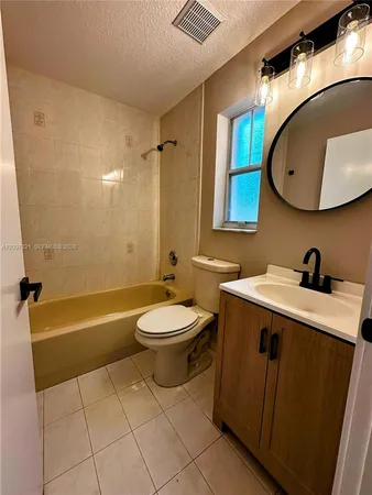 a bathroom with a toilet sink vanity tub and mirror