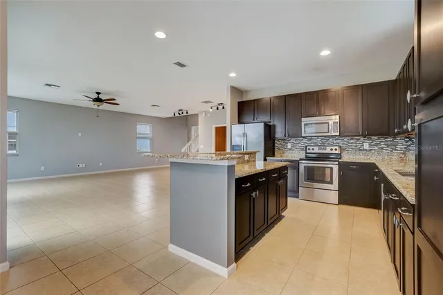 a kitchen with kitchen island granite countertop a sink stove and refrigerator