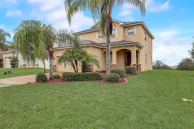 a view of a house with a big yard and palm trees