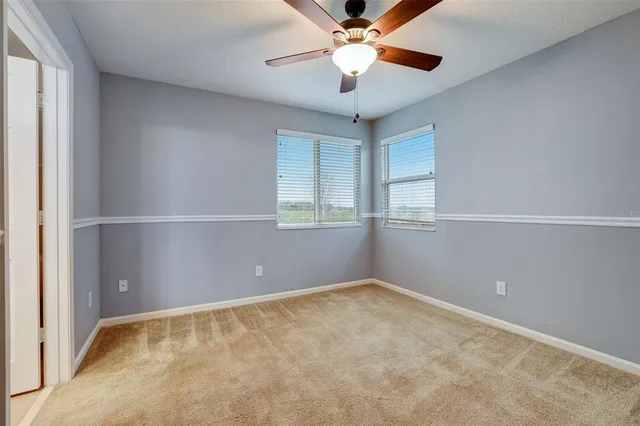 an empty room with a ceiling fan and a window