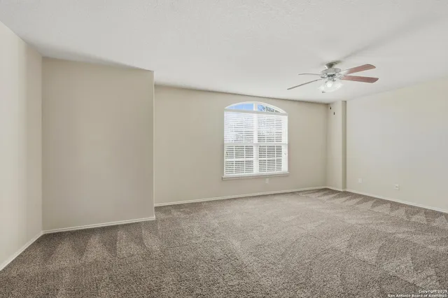 an empty room with windows and fan