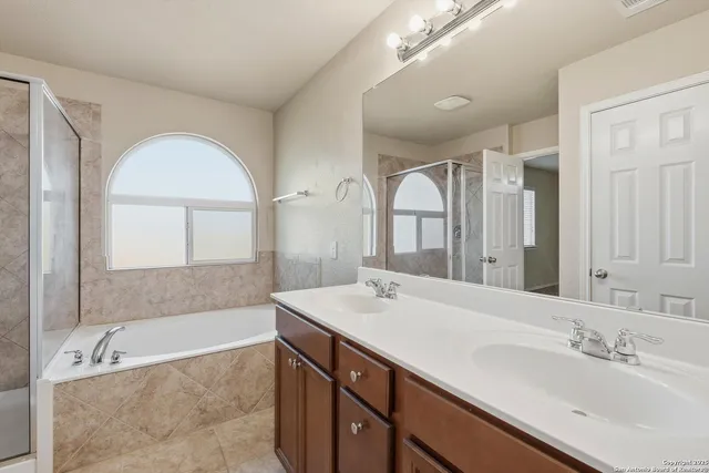 a bathroom with a tub a sink and mirror