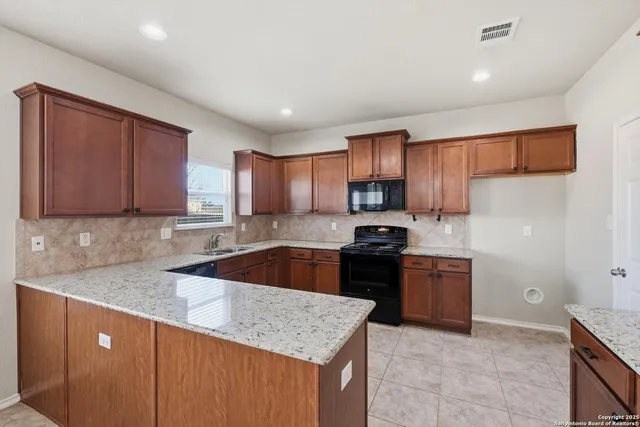 a kitchen with granite countertop a sink stove and refrigerator