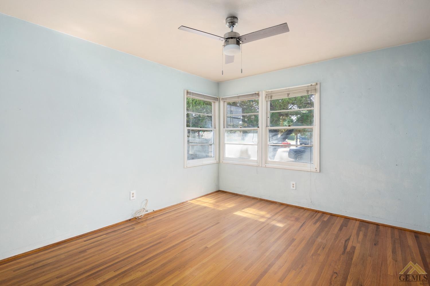 Undisclosed Address Bakersfield, CA 93301 - Photo 12 of 21 an empty room with wooden floor chandelier fan and windows