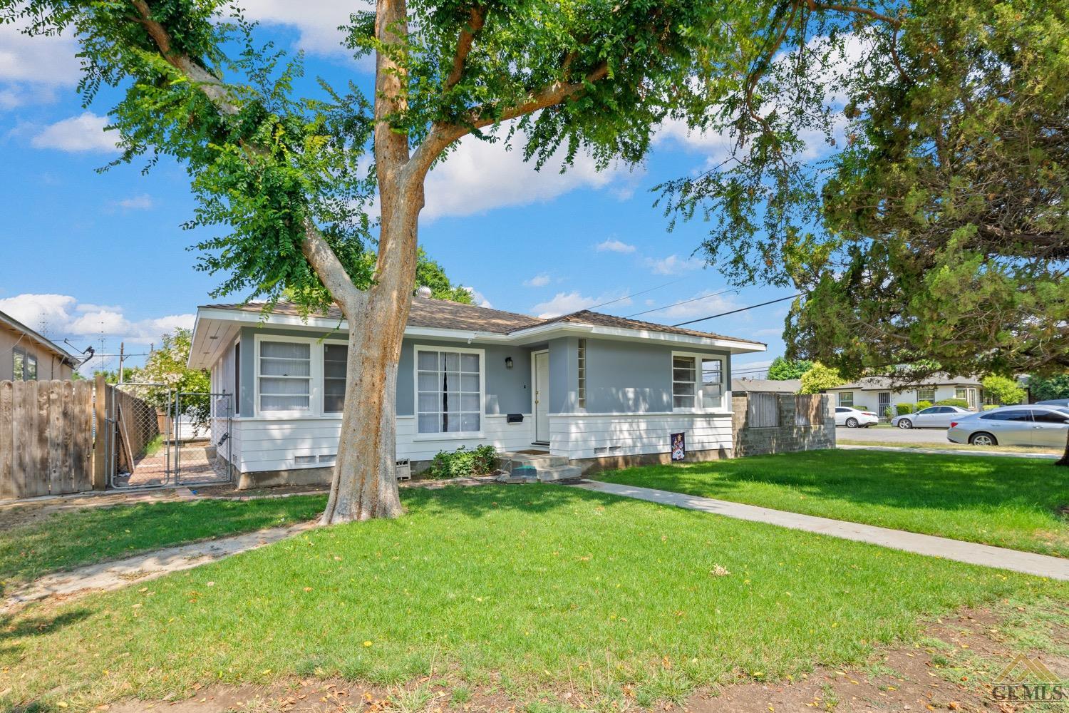 Undisclosed Address Bakersfield, CA 93301 - Photo 2 of 21 a front view of a house with a garden and trees