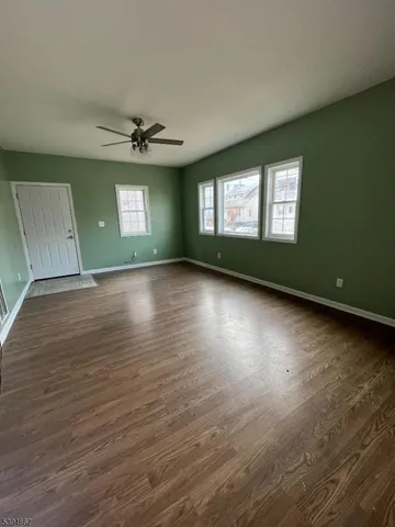 an empty room with wooden floor chandelier and windows