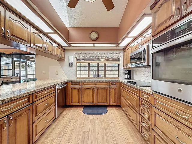 a large kitchen with stainless steel appliances granite countertop a stove and a sink