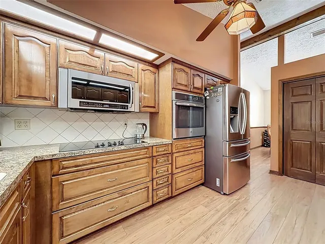 a kitchen with stainless steel appliances granite countertop a refrigerator oven a stove and a sink with wooden floor