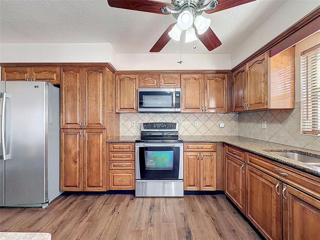 4289 Castle Avenue Spring Hill, FL 34609 - Photo 41 of 50 a kitchen with granite countertop wooden floors appliances and cabinets