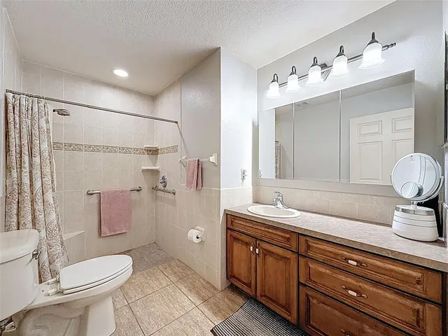 a bathroom with a granite countertop sink toilet mirror and shower