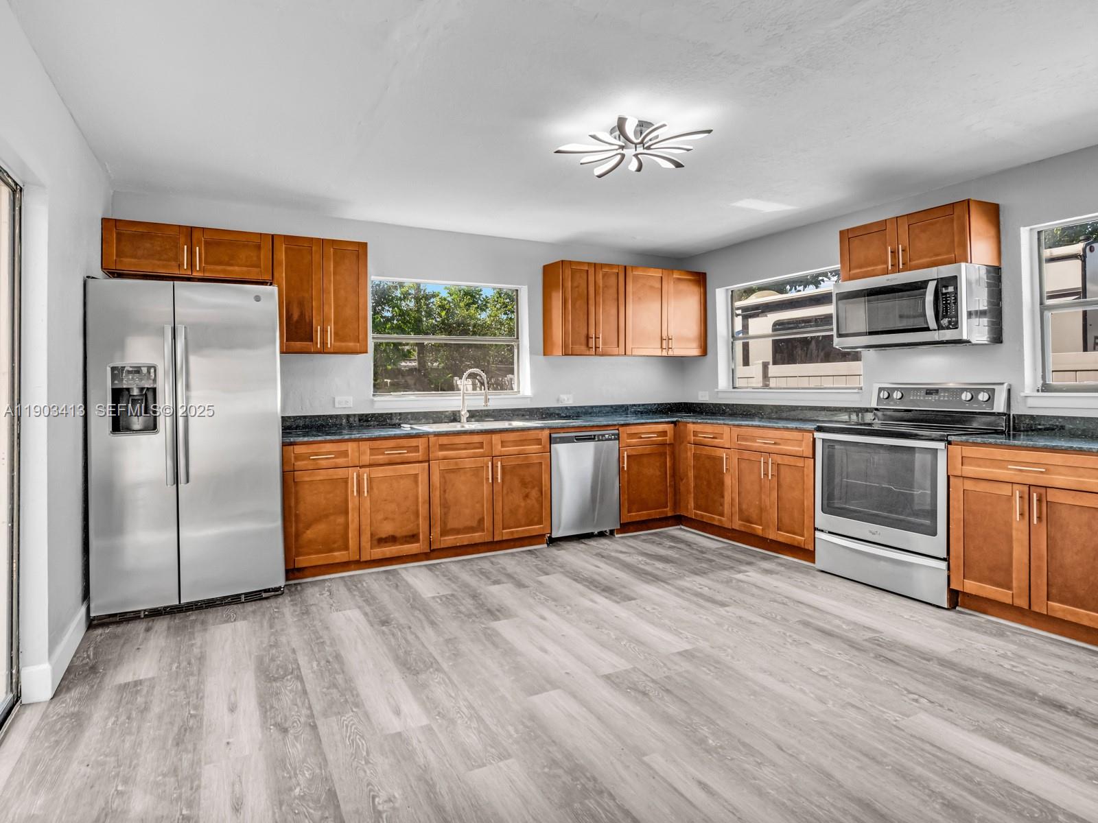 6238 Southwest 24th Street Miramar, FL 33023 - Photo 9 of 33 a kitchen with stainless steel appliances granite countertop a sink dishwasher a refrigerator with wooden cabinets and floor