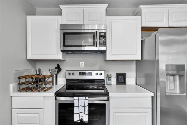 a kitchen with stainless steel appliances granite countertop white cabinets and a stove a oven with white countertops