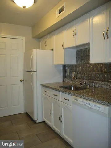 a kitchen with a sink a refrigerator and cabinets