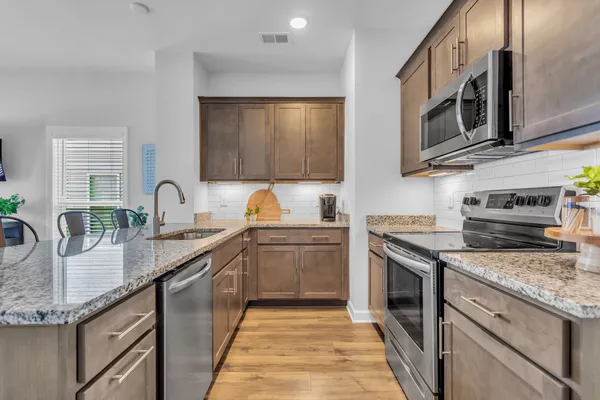 a kitchen with stainless steel appliances granite countertop a sink stove and microwave