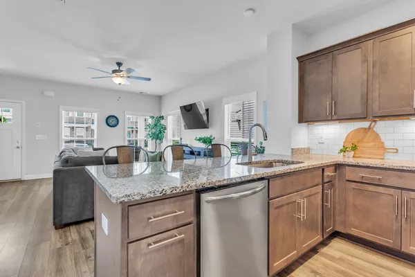 a kitchen with kitchen island granite countertop a sink cabinets and wooden floor