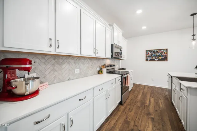 a kitchen with a white cabinets and wooden floor