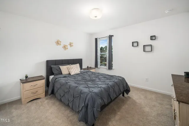 a bed sitting in a bedroom next to a window and a lamp