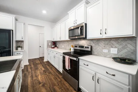 a kitchen with stainless steel appliances white cabinets and a stove top oven
