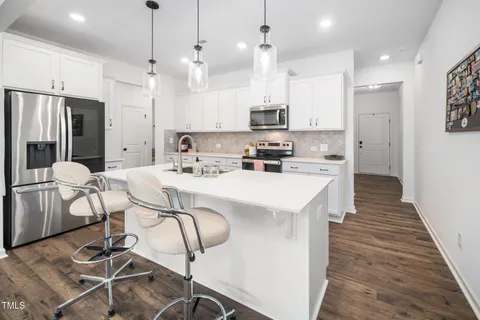 a kitchen with stainless steel appliances kitchen island a table chairs refrigerator and microwave