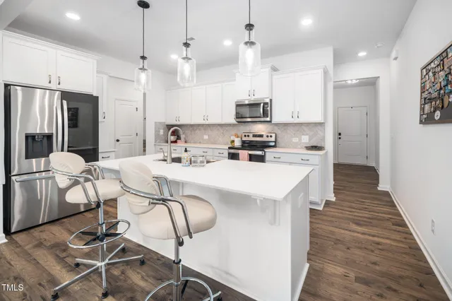 a kitchen with stainless steel appliances kitchen island a table chairs refrigerator and microwave