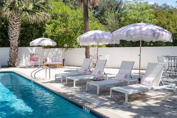 a view of a patio with chairs and umbrellas on a swimming pool