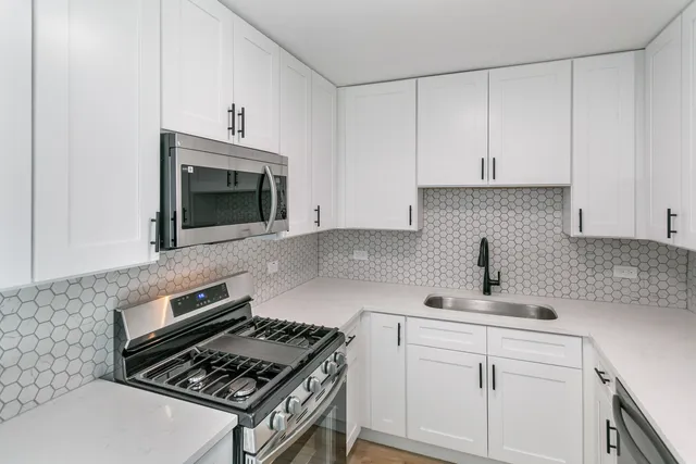 a kitchen with white cabinets and appliances