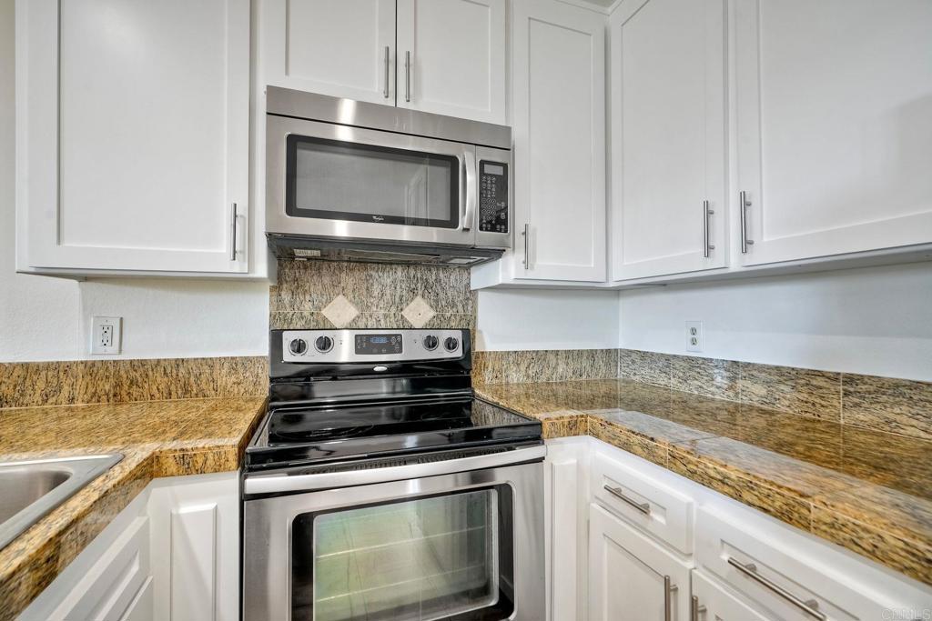 2251 Altisma Way, Unit 202 Carlsbad, CA 92009 - Photo 11 of 35 a kitchen with granite countertop a stove top oven microwave and cabinets