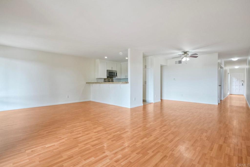 2251 Altisma Way, Unit 202 Carlsbad, CA 92009 - Photo 20 of 35 a view of empty room with wooden floor and a kitchen