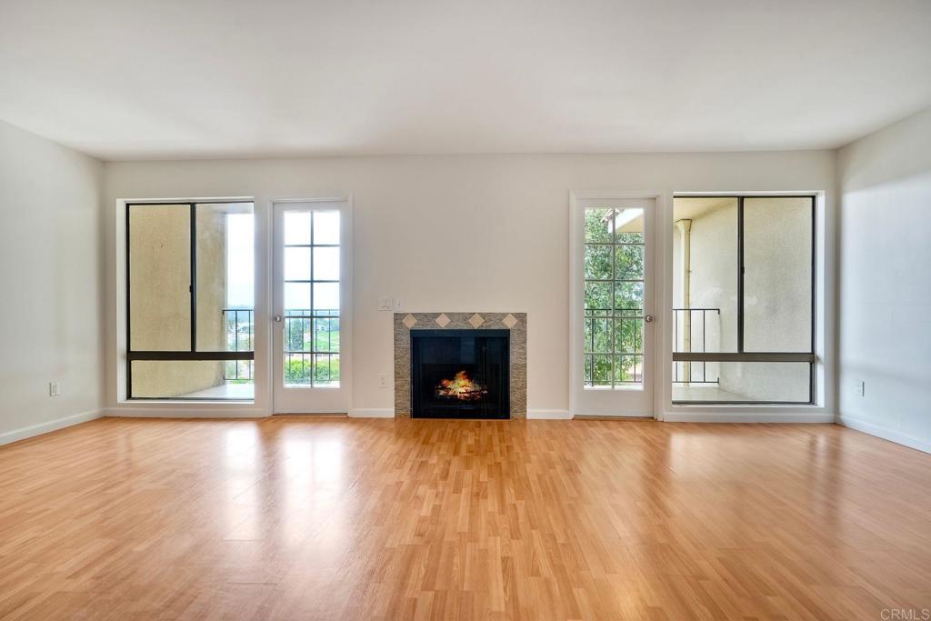 2251 Altisma Way, Unit 202 Carlsbad, CA 92009 - Photo 8 of 35 a view of an empty room with wooden floor and a window