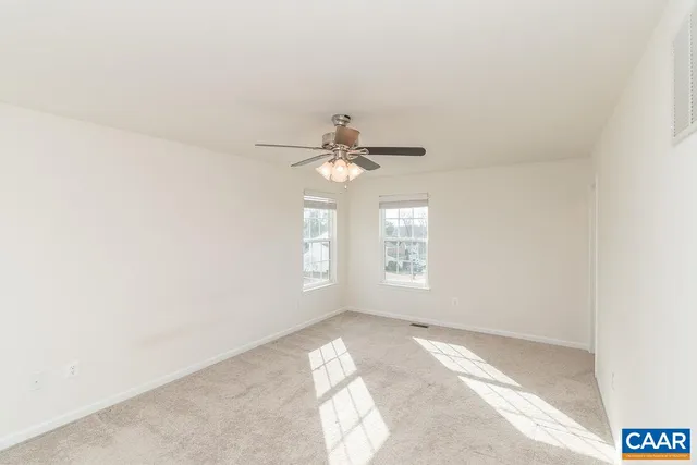 an empty room with windows and chandelier fan