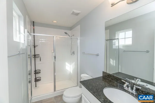 a bathroom with a granite countertop sink toilet mirror and shower
