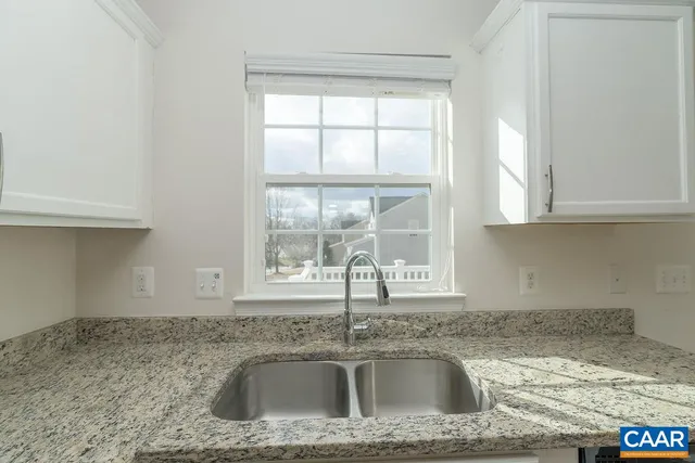 a kitchen with granite countertop a sink window and cabinets