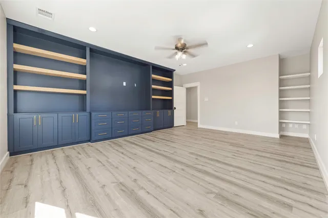 a view of empty room with wooden floor and ceiling fan