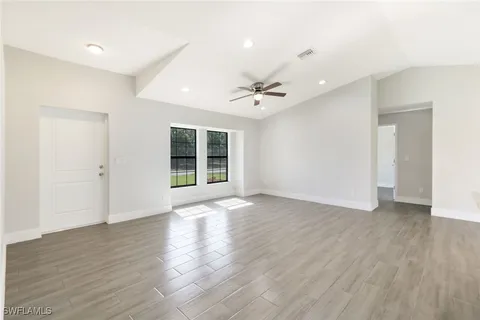 a view of an empty room with wooden floor and a window