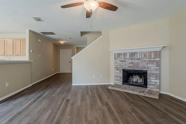 a view of an empty room with wooden floor fireplace and a window