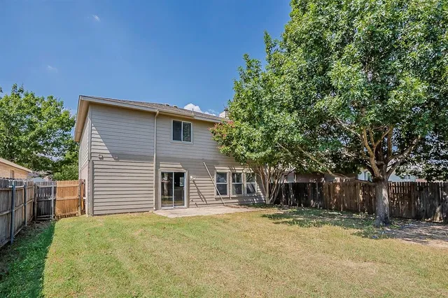 a backyard of a house with table and chairs under an umbrella