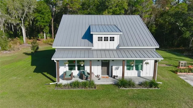 a aerial view of a house next to a big yard and large trees