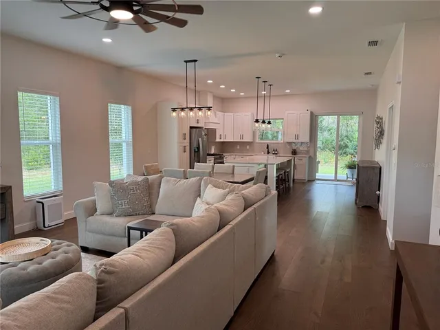 a kitchen with stainless steel appliances kitchen island a table chairs sink refrigerator and cabinets