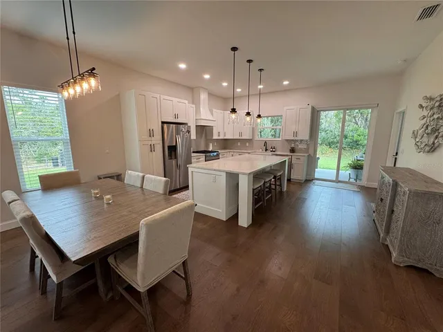 a kitchen with stainless steel appliances kitchen island a table chairs sink and microwave