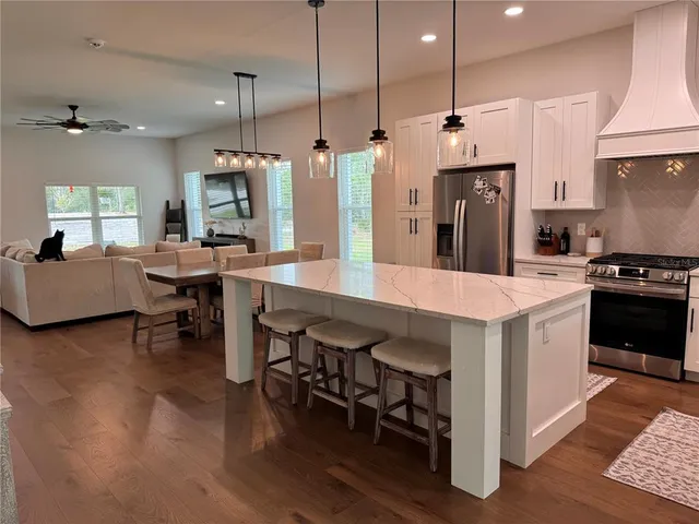 a large kitchen with kitchen island a stove a sink a center island a dining table and chairs