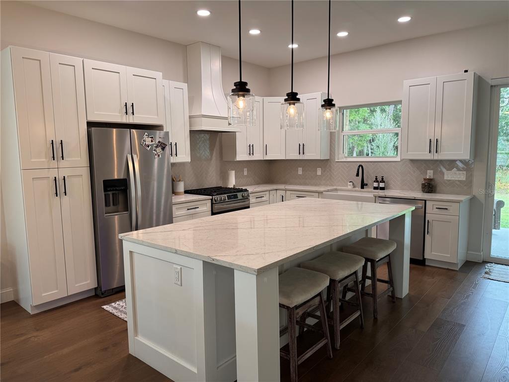 4275 Beacon Light Road Edgewater, FL 32141 - Photo 18 of 48 a kitchen with stainless steel appliances kitchen island a table chairs sink refrigerator and cabinets