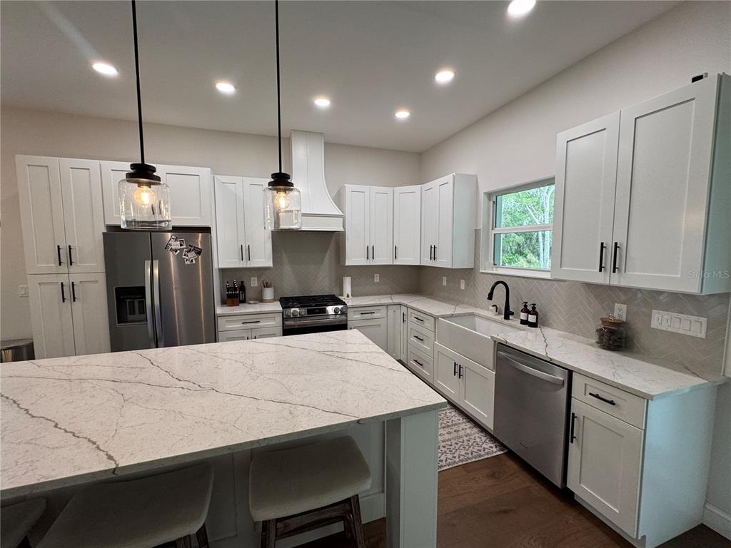 4275 Beacon Light Road Edgewater, FL 32141 - Photo 21 of 48 a kitchen with stainless steel appliances kitchen island a table chairs sink and microwave