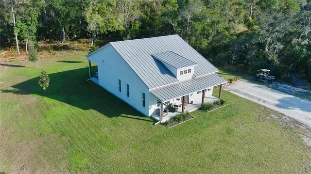 an aerial view of residential house with outdoor space and trees all around